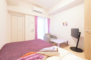 Un dormitorio con cama, escritorio, silla, televisor y armario.