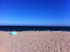 A beach with a large, empty sand area and a clear blue sky.