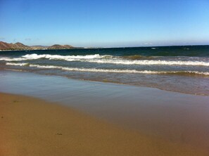 A beach with waves, sand, and distant mountains. - Chanh's House (Ninh Chu)