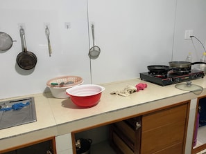 Une cuisine Ă©quipĂ©e dâune cuisiniĂšre, de casseroles, dâune passoire et dâun Ă©vier.