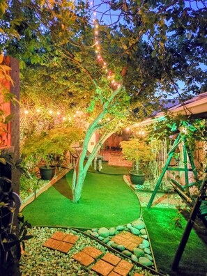 Ein Garten mit Baum, Teich und Lichterkette.