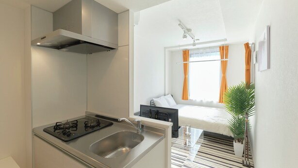 Une cuisine compacte équipée d’une cuisinière à gaz, d’un évier et d’une hotte de cuisine moderne.