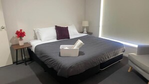 A neatly arranged hotel room with a bed, bedside tables, a chair, and a window.