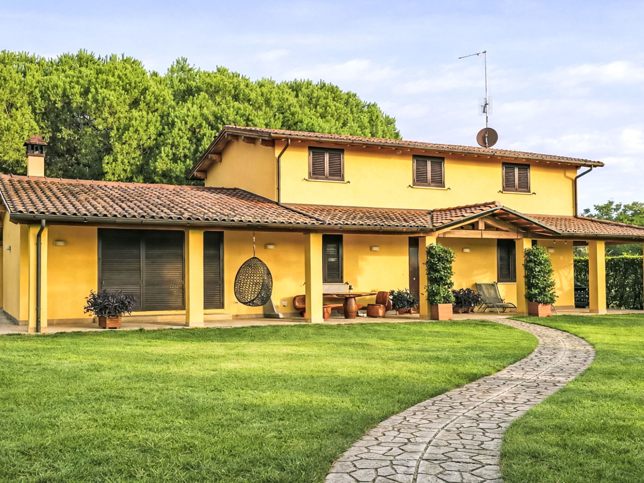 A two-story house with a tiled roof, a paved driveway, and a well-maintained lawn.