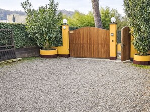 A gated entrance with a wooden gate, yellow walls, and potted plants. - "Casa di Max" by Interhome (Arezzo)