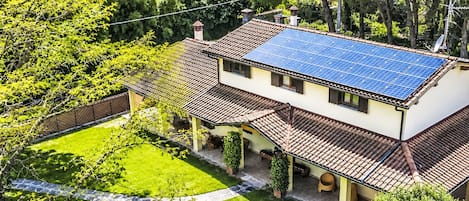 A two-story house with a solar panel roof, a well-maintained lawn, and a clear view of the surrounding greenery.