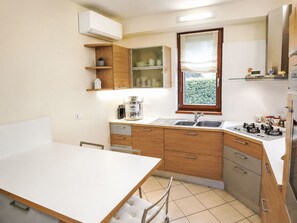 A compact kitchen with a white countertop, a sink, a window with a view, and wooden cabinets. - "Casa di Max" by Interhome (Arezzo)