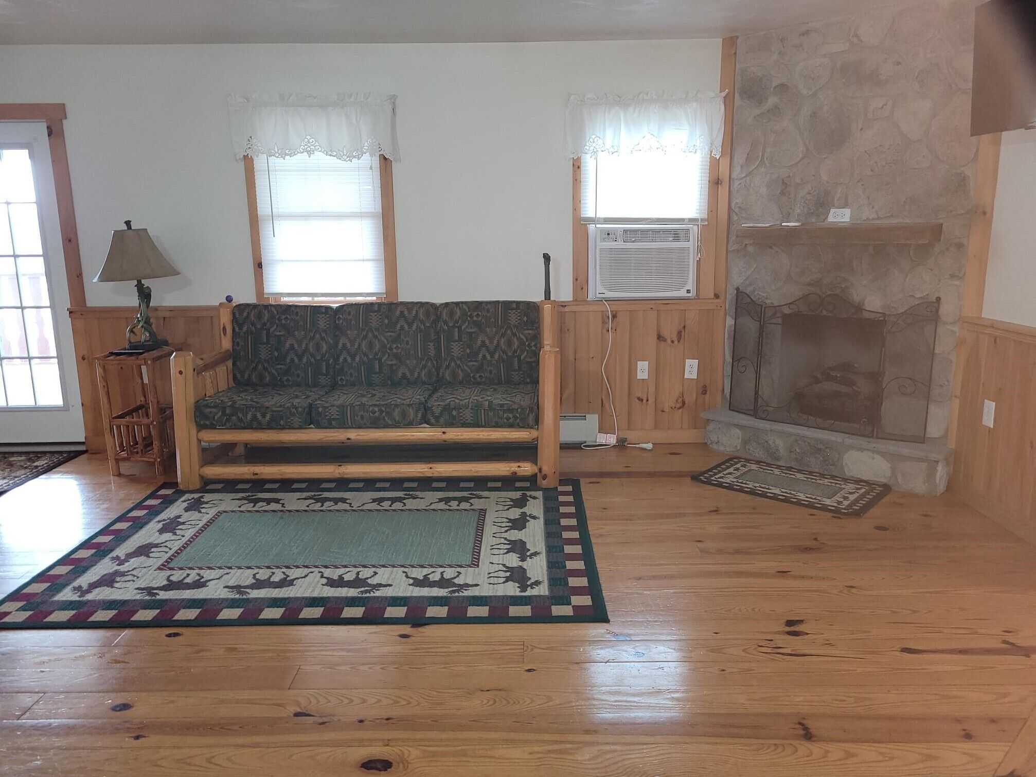 Una sala de estar con sofá, chimenea, alfombra y lámpara.