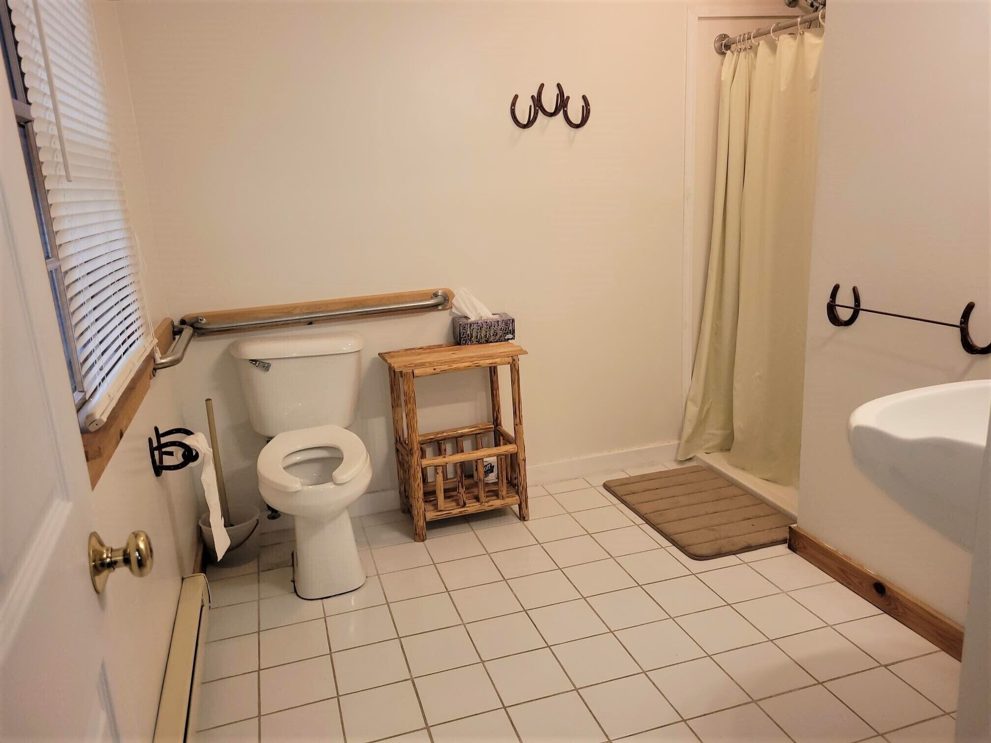 A bathroom with a toilet, a wooden side table, a shower curtain, and a bathtub.
