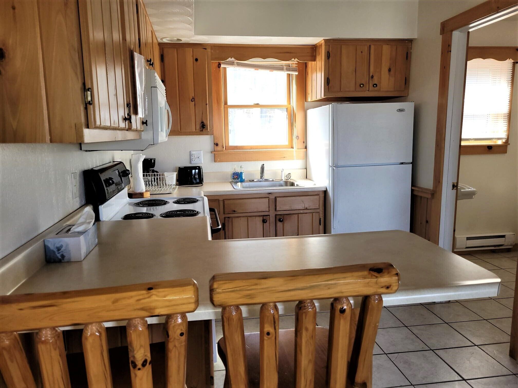 A compact kitchen with wooden cabinets, a white refrigerator, a stove, and a sink.