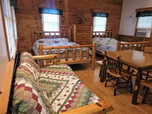 Une chambre de style cabane avec un lit en bois, une table à manger en bois et un canapé.