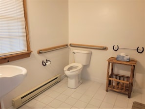 A bathroom with a toilet, a handrail, a towel rack, a radiator, and a small wooden table. - James Creek RV Resort (James Creek)