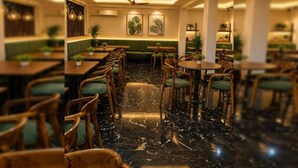 Un restaurante con cabinas, mesas redondas y asientos acolchados color verde.