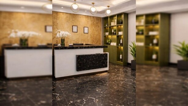 Un área de recepción con piso de mármol, mostrador de recepción y una pared con estantes que contienen varios objetos.