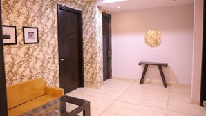 Una habitación con un sofá, una mesa de centro, un banco y dos puertas.