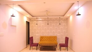 Una habitación con sofá, dos sillones, ventilador de techo y lámparas colgantes.