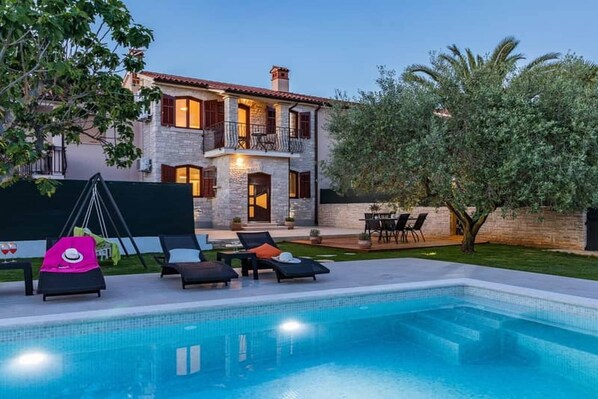 A two-story house with a swimming pool, outdoor seating, and a well-maintained garden. - Villa Pietra house situated Galižana (Croatia)