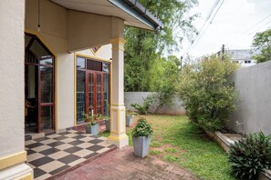 A building with a checkered floor, a covered entrance, and a garden area with potted plants.