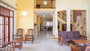 A spacious living area with a high ceiling, a staircase, and a kitchen in the background. - Kethmi Holiday Home (Pannipitiya)