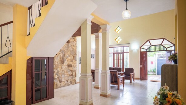 A spacious lobby with a staircase, a stone wall, and a view of the outside. - Kethmi Holiday Home (Pannipitiya)