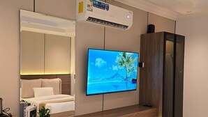 A modern living room with a flat-screen TV mounted on the wall, a sofa, a coffee table, and a cabinet. - Comfortable Diamond Apartments Al Hamra (Jeddah)