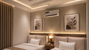 A hotel room with two beds, an air conditioning unit, wall-mounted artwork, and a bedside table with a lamp. - Comfortable Diamond Apartments Al Hamra (Jeddah)