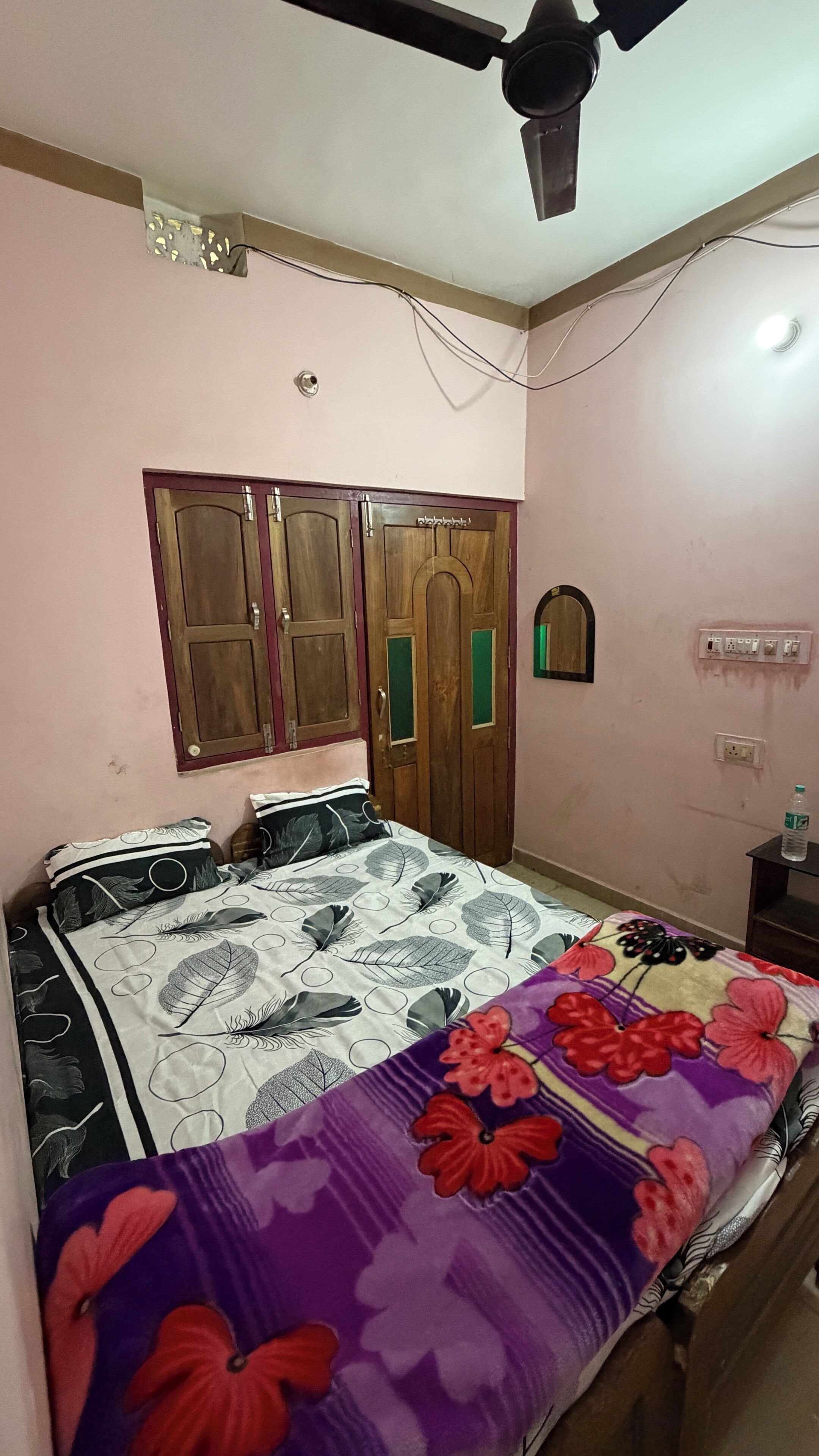 Una camera da letto con un letto, una ventola a soffitto, un armadio e una presa elettrica.