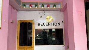 A reception area with a sign, a wooden door, and a window with a view of the street. - Hotel Akshni Palace (Purnia)