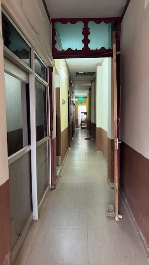 A long, narrow hallway with doors on both sides, some of which are open. - Hotel Akshni Palace (Purnia)