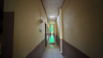 Um corredor estreito com um claraboia e um quarto iluminado em verde no final.