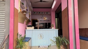 A reception area with a sign, a counter, and potted plants. - Hotel Akshni Palace (Purnia)