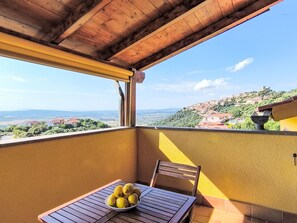 A balcony with a table and a bowl of lemons, overlooking a hillside with buildings. - Bellavista by Interhome (Scarlino)