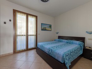 A bedroom with a bed, a nightstand, a painting on the wall, and a sliding glass door. - Bellavista by Interhome (Scarlino)