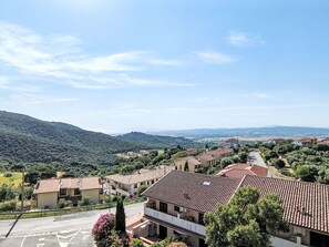A residential area with terracotta-roofed buildings, a clear sky, and a hilly landscape in the background. - Bellavista by Interhome (Scarlino)