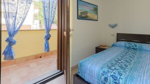 Ein Schlafzimmer mit einem Bett, einem Bild an der Wand und einem Balkon mit Vorhängen.