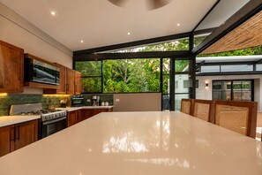 Una cocina moderna con una isla grande, armarios de madera y vistas a zonas verdes.