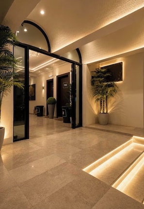Un moderno vestíbulo de hotel con techo curvo, una planta grande en maceta y una entrada bien iluminada.