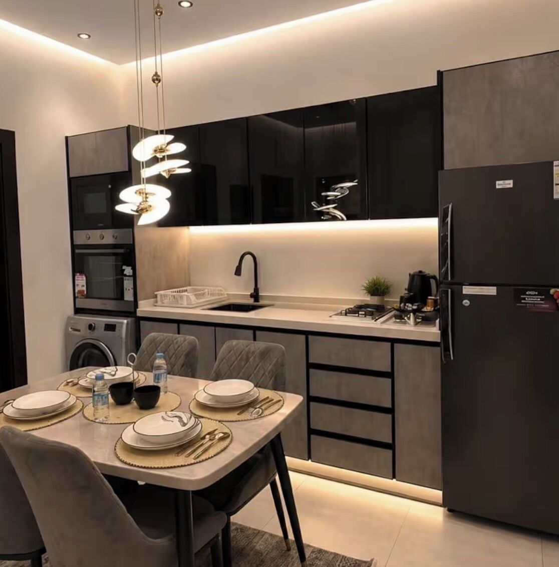 Cozinha moderna com ilha central, eletrodomésticos embutidos e iluminação pendente.