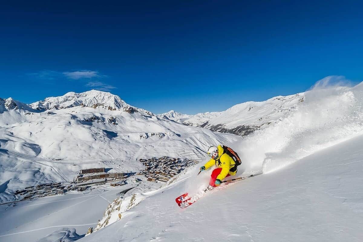 A snowboarder on a snowy slope with a mountain backdrop.