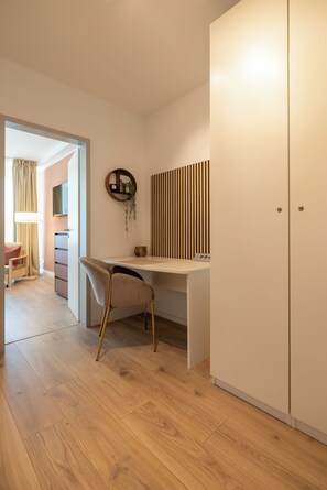 Quarto com escrivaninha, cadeira, guarda-roupa e um espelho na parede.