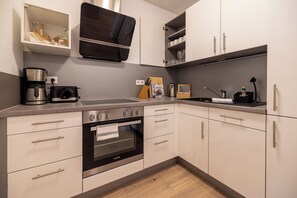Cozinha moderna com forno embutido, máquina de café e torradeira.