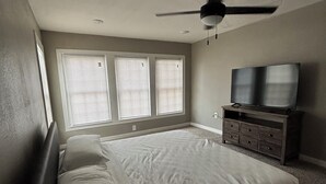 Une chambre à coucher avec un lit, une commode, un ventilateur de plafond et un téléviseur.