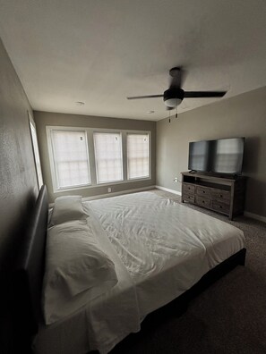 Ein Schlafzimmer mit einem Bett, einem Schminktisch, einem Deckenventilator und einem Fernseher.