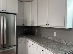 Eine Küche mit weißen Schränken, einem Edelstahlkühlschrank, einem Mixer und einem Toaster.