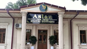 Un edificio con un letrero que dice 'Aslan Tea Shop Hostel Boutique'.