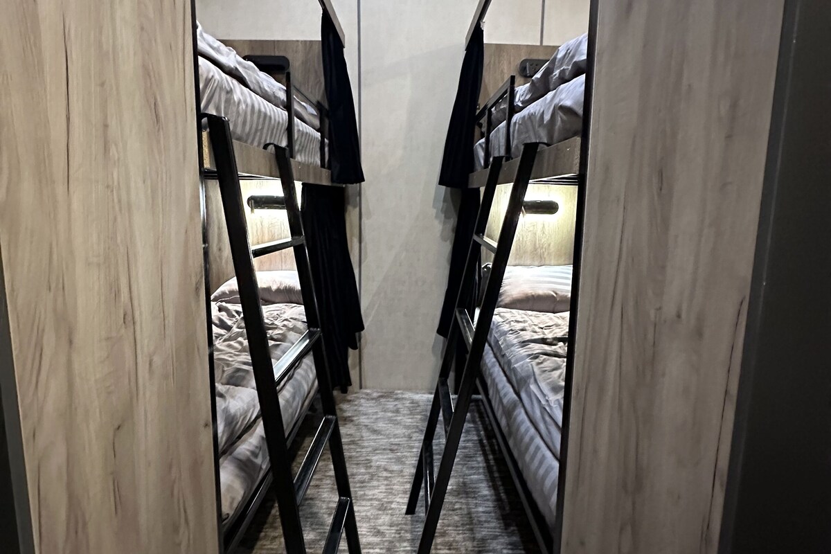 A narrow room with bunk beds, wooden walls, and a tiled floor.