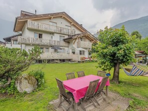 A two-story chalet with a balcony, a dining area with a table and chairs, and a hammock. - Casa Roby by Interhome (Pinzolo)