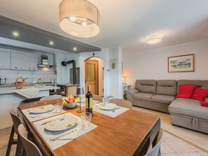 A modern kitchen with a dining area, a sofa, and a painting on the wall. - Casa Roby by Interhome (Pinzolo)
