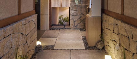A stone pathway leading to a room with a wooden ceiling and a stone wall.