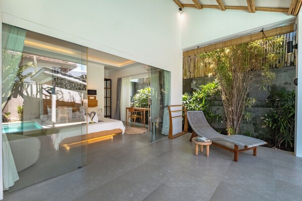 A modern room with a glass wall, a bed, a lounge chair, and a small table. - Bingin Villas: Luxury, Concierge & Security (Badung)